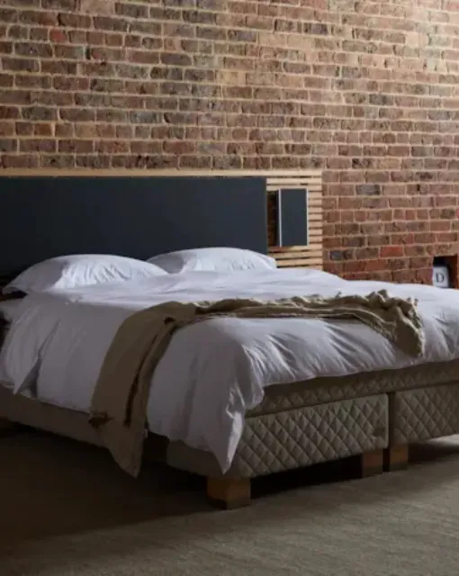Bed with upholstered fabric and wood headboard by Duxiana